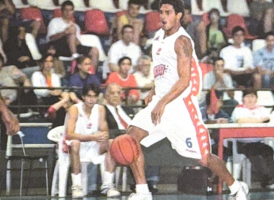 Jogador de camisa branca número 6 driblando diante da arquibancada